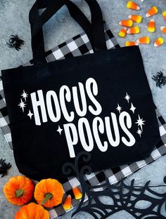 a black bag with hoccus pocus on it next to candy and pumpkins