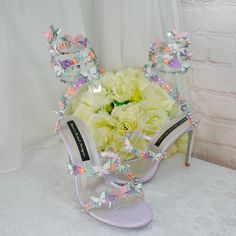 a pair of high heeled shoes with flowers in the background