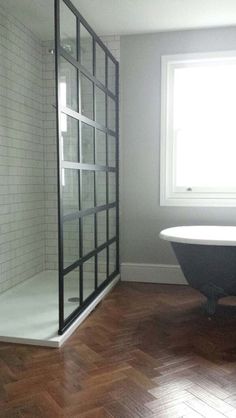 a bath tub sitting next to a window on top of a hard wood floored floor