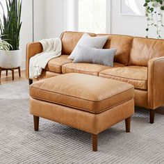 a tan leather couch and ottoman in a living room