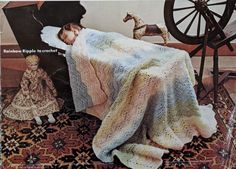 a child laying in bed under a blanket next to a toy horse and rocking chair