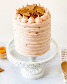 a cake with frosting and gold stars on top is sitting on a white pedestal