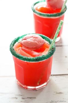 two glasses filled with watermelon drink on top of a white wooden table next to each other