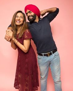 a man and woman are posing for a photo in front of a pink background with their arms around each other