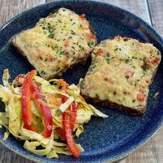 two pieces of bread on a blue plate with vegetables and coleslaw next to it