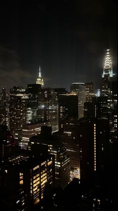 the city skyline is lit up at night, with skyscrapers in the foreground