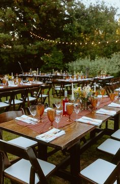 a long table set up with wine glasses and place settings for an outdoor dinner party