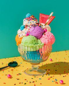 an ice cream sundae with sprinkles and colorful toppings on a table