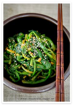 a bowl filled with green vegetables next to chopsticks