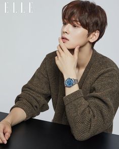 a young man sitting at a table with his hand on his chin and looking off to the side