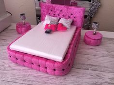 a bed made out of pink material with pillows and decorations on the headboard in front of it