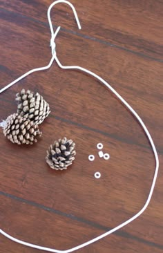 two pine cones are hanging from a wire on a wooden table next to some beads