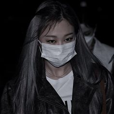 a woman wearing a face mask in the dark with long black hair and leather jacket