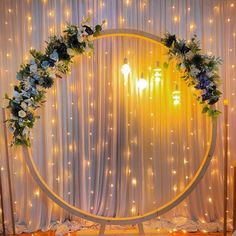 a circle with flowers and lights on the wall in front of a curtained backdrop