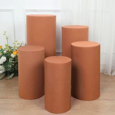 four round stools sitting next to each other on a wooden floor with flowers in the background