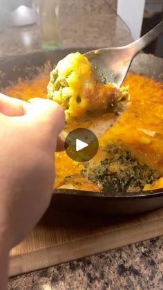 a person is spooning food out of a pan with broccoli and cheese