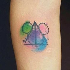 a watercolor tattoo on the leg of a woman's lower arm with an abstract triangle and two circles