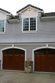 two garage doors are open in front of a gray house with white trim and windows