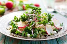 a white plate topped with broccoli and radishes on top of a wooden table