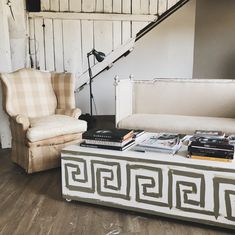 a living room with a couch, chair and books on top of the coffee table