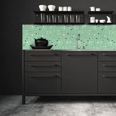 a kitchen with green speckles on the wall and black cabinets, including a sink