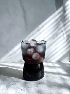 a glass filled with liquid sitting on top of a white counter next to a wall