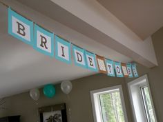 a bridal banner hanging from the ceiling in a living room with balloons and streamers