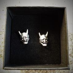 two silver cat earrings in a black box