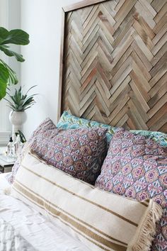 a bed with two pillows on top of it next to a potted green plant