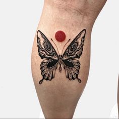 a woman's leg with a butterfly tattoo on it and a red dot in the middle