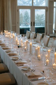 a long table is set up with candles and place settings for dinner guests to enjoy