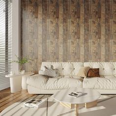 a white couch sitting in front of a wooden wall next to a table and chair