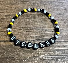 "Black, yellow, white 6/0 beads, 7mm letter beads, stretchy elastic, can be made to any size Size Guide: 5\" - Little Kids 6\" - Small 7\" - Average Adult 8\" - Large" Steelers Bracelet, Football Bracelet, Yellow Bracelet, Sports Bracelet, Diffuser Bracelets, Football Gifts, Letter Beads, Awareness Ribbons, Flower Bracelet