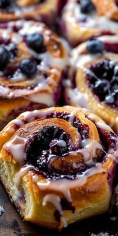 blueberry cinnamon rolls with icing drizzled over them on a cutting board