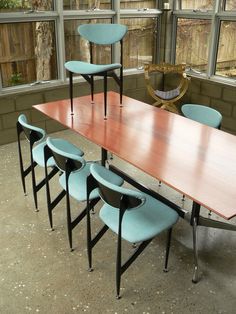 a long table with six chairs around it in front of a large window and some windows