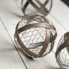 three metal balls with wire wrapped around them on a white wooden surface, one is hanging from the ceiling