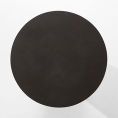 a round black table sitting on top of a white wall