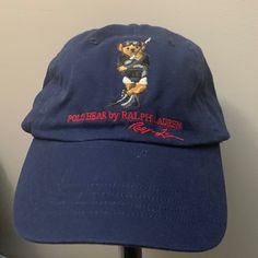 Navy Blue Designer Cap With Designer Signature. Embroidered Polo Bear Emblem, New Never Worn Navy Cap With Embroidered Logo, Navy Visor Hat With Embroidered Logo, Blue Baseball Cap With Embroidered Logo Visor, Casual Blue Hats With Embroidered Logo, Navy Embroidered Baseball Cap, Blue Flat Bill Hat With Embroidered Logo, Navy Embroidered Cap, Blue Hats With Embroidered Logo, Blue Hat With Embroidered Logo