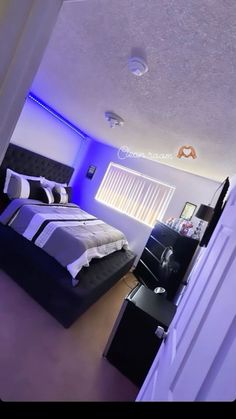 a bed room with a neatly made bed and purple lighting