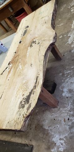 a wooden bench sitting on top of a floor next to a piece of metal and wood