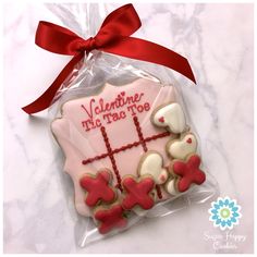 a decorated cookie in the shape of a cross and teddy bears with a red ribbon tied around it