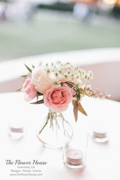 a vase filled with flowers sitting on top of a table next to two shot glasses