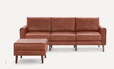 a brown leather couch and footstool sitting next to each other