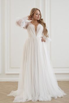 a woman in a white dress posing for the camera with her hands on her head