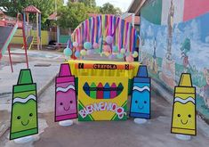 some crayons are lined up in front of a carnival booth with balloons on it