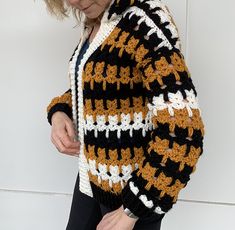 a woman wearing a crocheted jacket and black pants