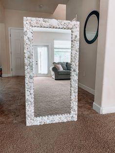 a large mirror with shells on it in the middle of a living room and hallway