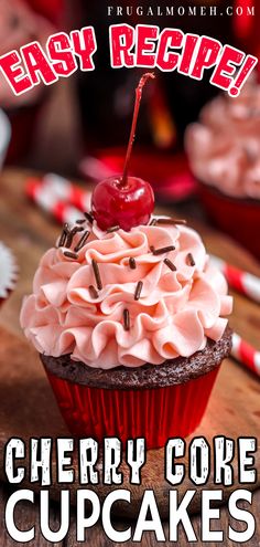 a cupcake with pink frosting and a cherry on top sitting on a wooden table