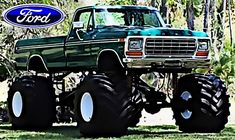 an old ford monster truck with huge tires on it's flatbed in the grass