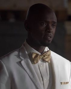 a man wearing a white suit and yellow bow tie